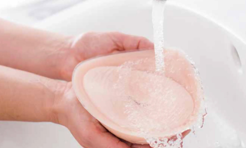 A person cleaning breastforms with mild soap and water.