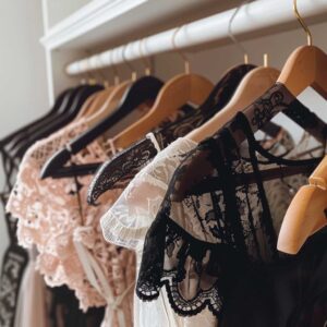 Collection of crop tops and lace blouses on hangers, representing essential femboy wardrobe tops.
