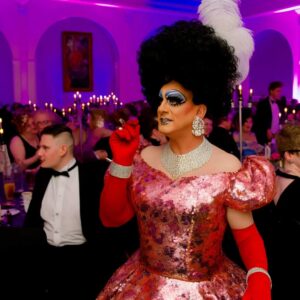Drag queen in a flamboyant costume at a drag ball, representing the influence of 1980s-1990s drag culture on femboy fashion.